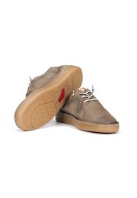 Zapatos bajos de malla marrones con una superficie texturizada, cordones blanco roto y una suela de goma con un patrón de dibujo y acento rojo.