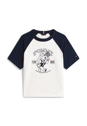 Tricou raglan alb și bleumarin cu un câine desen animat care joacă baschet, cu textul „TOMMY”, „1985” și „The Buzzer Beater” pe față.
