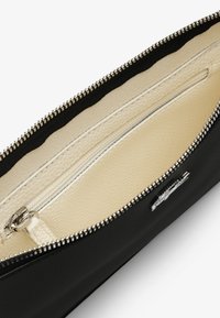 Pochette nera con cerniera, dotata di un esterno testurizzato, interno crema e cerniera argento. Include un compartimento interno e un accento con logo.