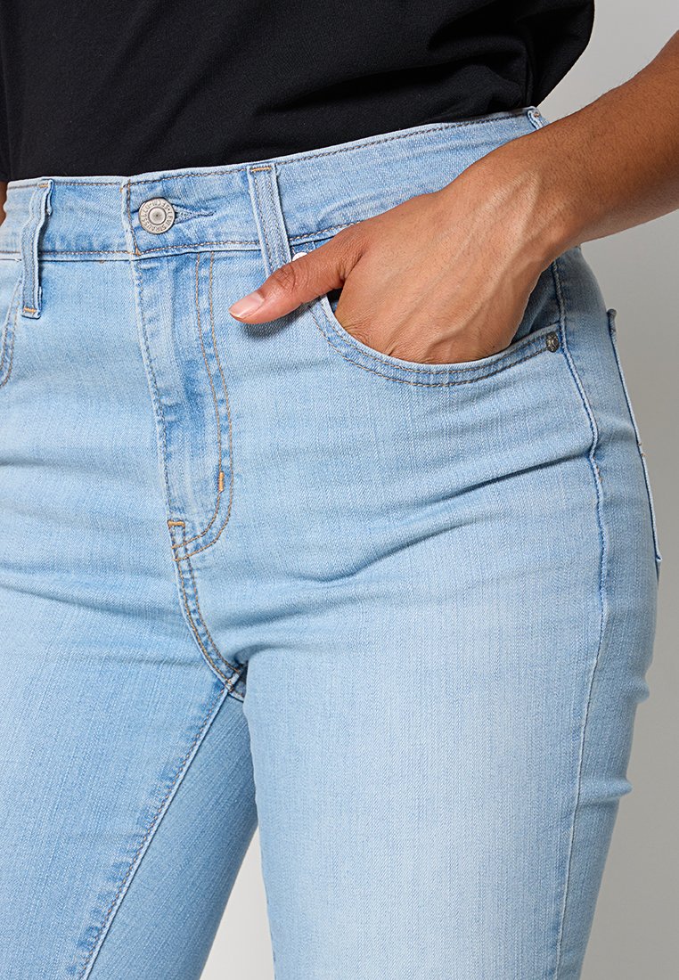 Helle blaue hochgeschnittene Jeans im Slim-Fit, aus Denim mit glatter Textur gefertigt. Mit Fronttaschen und klassischem Knopfverschluss.