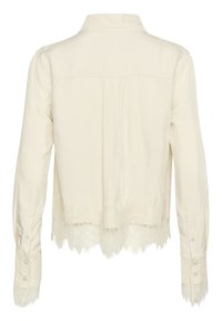 Cremefarvet bluse med krave, lange ærmer og blondedetaljer ved kanten og ærmerne for ekstra struktur og detaljer.