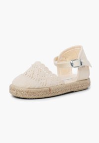 Beige Espadrille-Schuh mit offenem Strick-Obermaterial, gewelltem Design, Knöchelriemen mit silberner Schnalle und geflochtener Jutesohle.