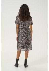 Sheer leopard print dress with short sleeves, cinched waist, and midi length, paired with black ankle boots. Neutral color palette.