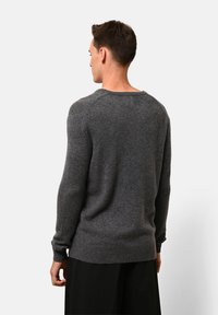 Grauer Strickpullover mit Rundhalsausschnitt, gerippten Bündchen und Saum. Die Textur wirkt weich und dick, ideal für kühleres Wetter.
