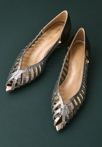 Baleriny szpiczaste z metalicznymi szarymi akcentami, otwartymi bokami i dekoracyjnymi wycięciami. Gładka wewnętrzna wyściółka i niski obcas.