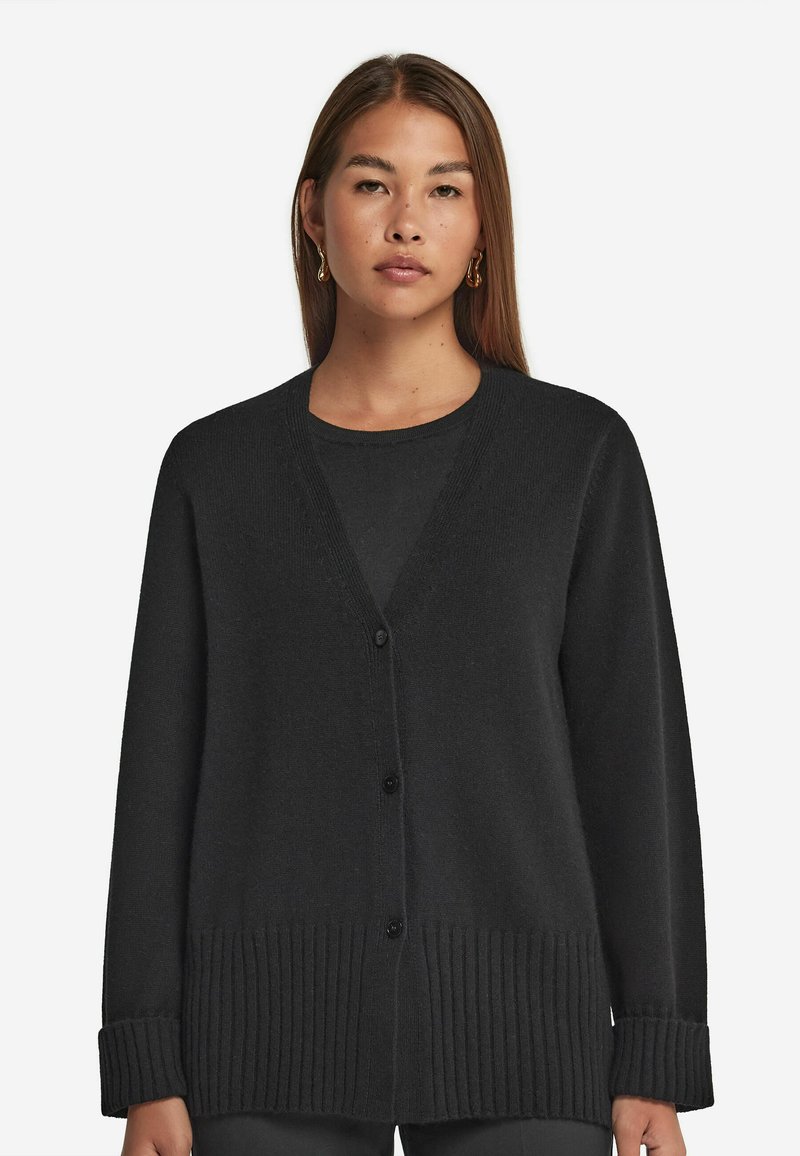 Czarny kardigan wykonany z miękkiego materiału, z dekoltem w kształcie litery V, prążkowanym dołem i mankietami, oraz z przodu zapinany na guziki. Gładka tekstura, luźny krój.
