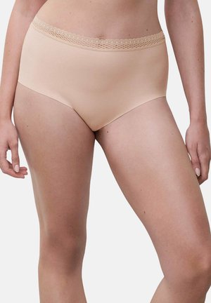 Woman wearing nude-colored seamless hipster underwear with lace trim on neutral background.