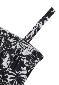 Abito a fiori in bianco e nero con arricciatura elastica, spalline sottili e morbida texture del tessuto, caratterizzato da disegni di foglie e pois.