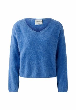 Pull en cachemire bleu à col en V, avec des manches longues, arborant une texture douce et duveteuse ainsi qu'un design court. Étiquette visible au niveau du col.