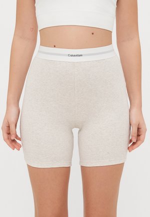 Calvin Klein beige ribbed shorts with a gray waistband featuring the brand logo. Material appears soft with a fitted design.