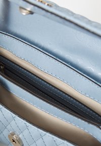 Portafoglio azzurro chiaro realizzato in materiale testurizzato, con numerosi scomparti, tra cui una sezione con zip e una fodera interna liscia.