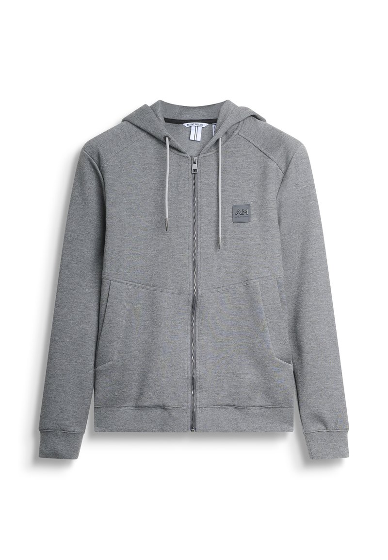 Sudadera gris con cremallera y capucha, hecha de tela suave. Presenta un parche con logo, bolsillos en la parte frontal y cordones en la capucha.