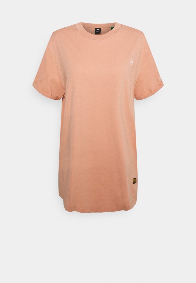 Světle broskvové tričko vyrobené z bavlny, s kulatým výstřihem, krátkými rukávy a malým logem na hrudi. Na spodním lemu je opatřeno štítkem.