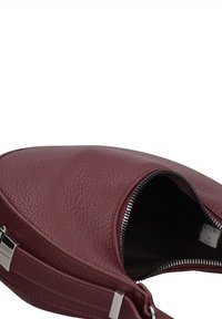 Sac à main en cuir bordeaux avec une finition texturée, une fermeture éclair et des éléments en métal argenté. Ouverture supérieure dévoilant une doublure intérieure foncée.