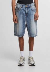 Wyblakłe niebieskie krótkie spodenki dżinsowe do kolan o luźnym kroju. Posiadają design z pięcioma kieszeniami, zapięcie na guziki oraz kontrastujące przeszycia.