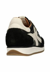 Zwart-wit vetersneaker met een bovenwerk van suede en leer, geschulpte accenten en een witte tussenzool. Zichtbare stiksels op de hak.