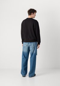 Pulover negru cu guler rotund, asociat cu blugi de culoare albastră deschisă, cu o croială lejera, având un model estompat și design drept.