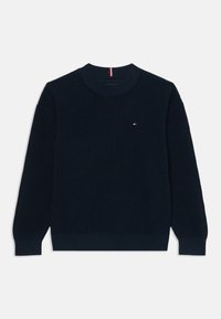 Pull en tricot bleu marine avec un col rond et des poignets côtelés. Présente un petit logo sur la poitrine et un tissu texturé.