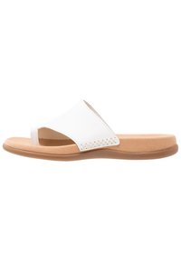 White slide sandal with a textured leather upper, open toe design, and a cushioned tan sole. Features woven detailing on the side.