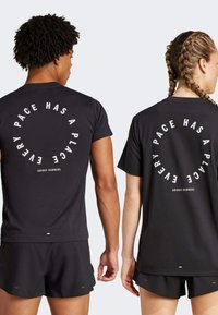 Svarta sporttröjor med rund vit text på ryggen, som står "VARJE TEMPO HAR EN PLATS," i kombination med svarta shorts.