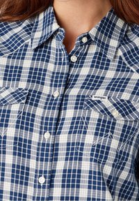 Camicia a quadri blu e bianca Wrangler con chiusura a bottoni, colletto a punta, due tasche sul petto e bottoni bianchi; texture in cotone.
