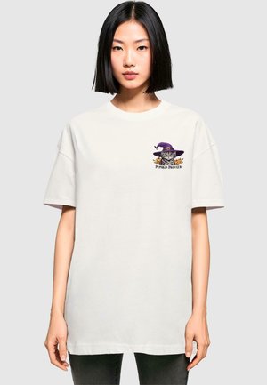 Weißes Baumwoll-T-Shirt mit lockerer Passform. Auf der Brust befindet sich ein farbenfrohes Motiv eines Katers mit einem lila Hut und Kürbissen. Kurze Ärmel.