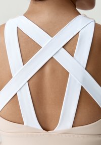 Sukňovo športový top s telovou základňou a bielymi prekrižovanými popruhmi. Hladká textúra s čistým, minimalistickým dizajnom a bez viditeľného kovania alebo ozdôb.