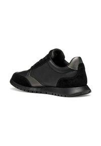 Baskets noires en cuir et daim, avec une semelle texturée et un design sportif, mettant l'accent sur le profil de la chaussure.