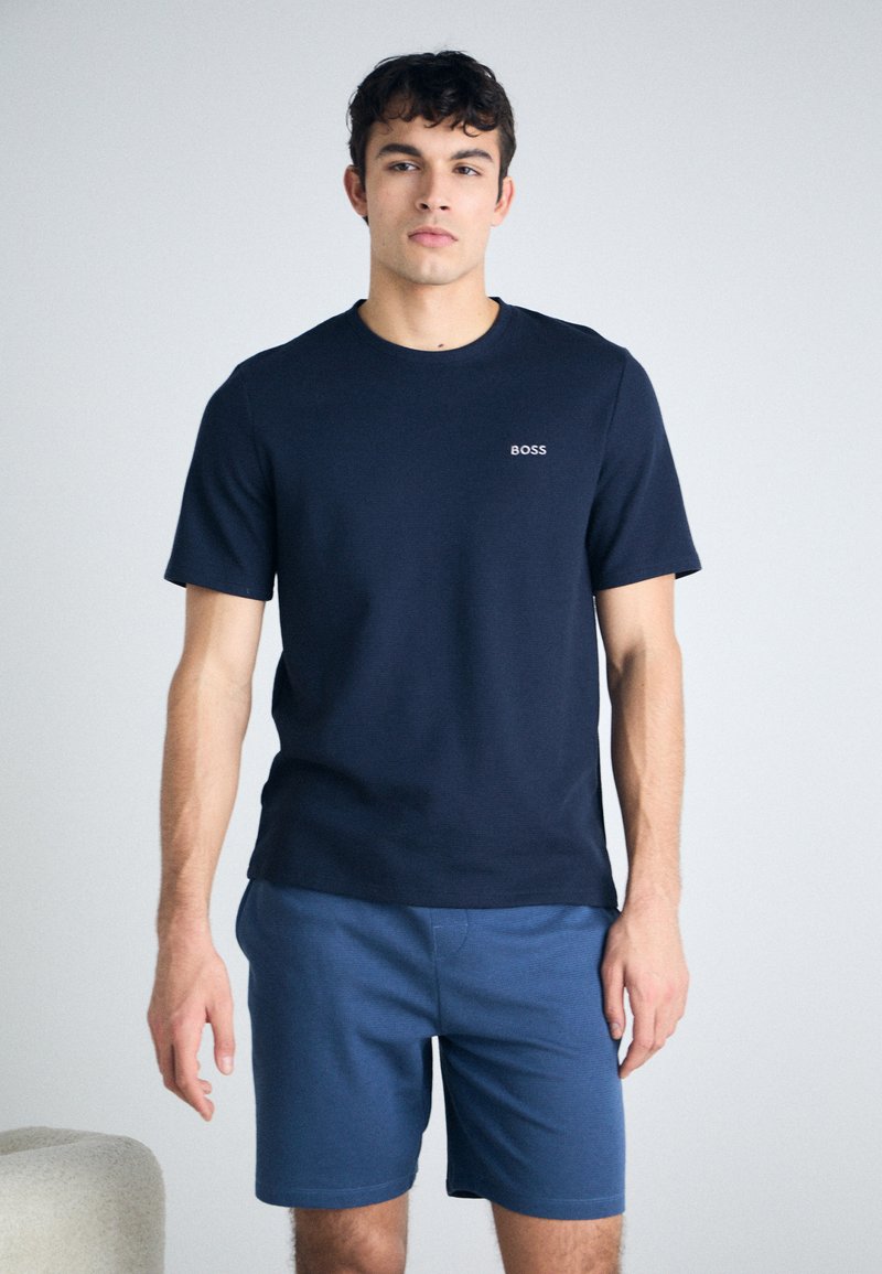 T-shirt azul marinho feito de material suave, com gola redonda, mangas curtas e um pequeno logotipo branco "BOSS" no lado esquerdo do peito.