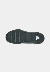 Schwarze und dunkelgrüne Schuhsohle mit dreieckigem Profilmuster und einem weißen dreieckigen Logo in der Nähe der Ferse auf einem schlichten weißen Hintergrund.