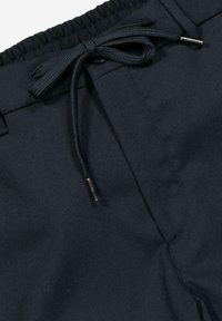 Dark navy pants featuring an elastic waistband and a drawstring tie. The fabric is smooth with a matte finish and minimal stitching.