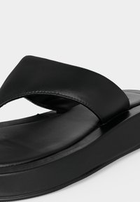 Sandale plateforme noire avec large bride rembourrée et semelle intérieure coussinée, conçue pour le confort et un usage décontracté.