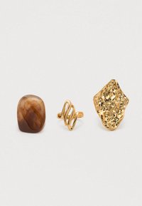 Trois bagues : une pierre brune à surface lisse, un anneau en or torsadé, et une pièce en or texturée avec des motifs complexes.