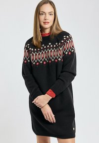 Robe pull noire avec des motifs géométriques rouges et blancs sur le yoke, des poignets côtelés et un col rond. Matériau doux et texturé.
