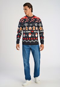 Stickad tröja med marinblå grund, med julikoner som jultomte, karameller och pepparkaksgubbar i rött, vitt och guld. Rund hals, långa ärmar.