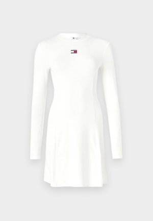 Abito bianco a maniche lunghe fatto di tessuto a costine. Presenta una scollatura rotonda e una piccola etichetta con logo sul petto. Vestibilità aderente con un orlo svasato.