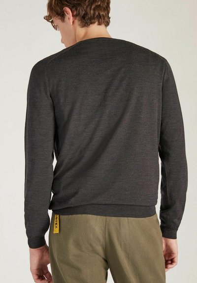 Pull gris à manches longues avec col rond, en tissu texturé, doté de poignets et d'un ourlet côtelés. Porté avec un pantalon vert olive.