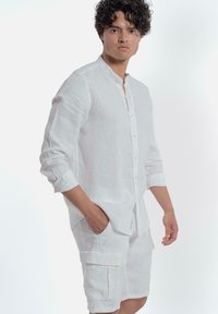 Witte linnen overhemd met een Mandarin-kraag, lange mouwen opgerold, en bijpassende cargoshorts met zakken en een comfortabele pasvorm.
