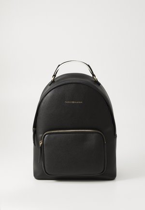 Sac à dos en cuir noir de forme ronde, avec une poche avant, une fermeture éclair dorée et une poignée sur le dessus. Logo embossé à l'avant.