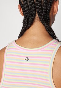 Striped tank top featuring pastel colors, made of soft fabric. Notable details include a small star logo and a round neckline.