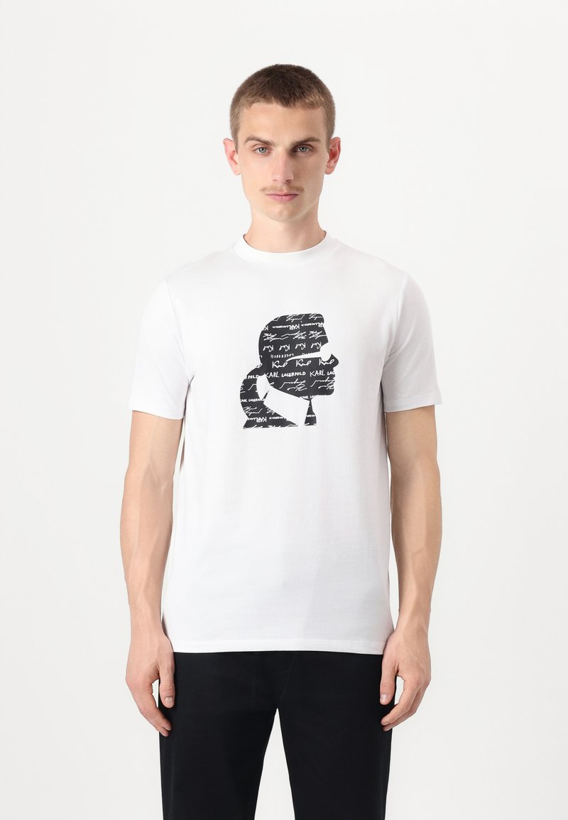 Hvit bomulls T-skjorte med svart grafisk design av en silhuett med håndskrevet tekst. Rund hals og korte ermer.