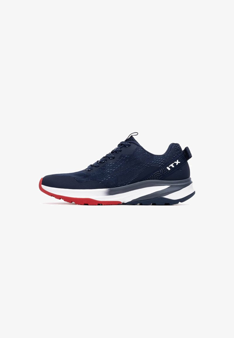 Zapatilla deportiva azul marino con parte superior texturizada, acento rojo en la punta y una entresuela blanca. Presenta cordones y elementos reflectantes.