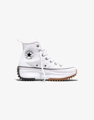 Valkeat Conversen korkeavartiset tennarit, joissa on paksu, sahalaitainen musta-ruskea pohja, metalliset nauhojen reiät ja Converse All Star -logo nilkassa.