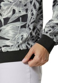 Langsleeve top met een grijs en zwart abstract bladpatroon, voorzien van een zwarte geribde manchette en zoom, gemaakt van soepel stof.