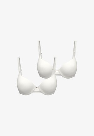 Zwei weiße gepolsterte BHs mit verstellbaren Trägern und kleinen dekorativen Charms, die in der Mitte zwischen den Körbchen angebracht sind, auf weißem Hintergrund dargestellt.