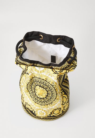 Sac seau avec un motif paisley noir, jaune et blanc, surmonté d'un cordon noir et de matériel doré. L'intérieur est blanc.