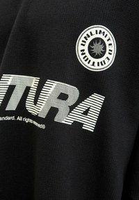 Tessuto nero con testo bianco audace "VENTURA" e dettagli lineari. Patch rotonda ricamata con la scritta "UNLIMITED EDITION" e icona del sole.