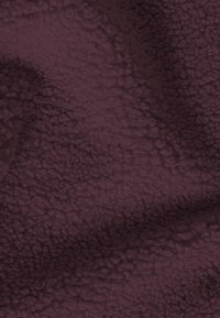 Tissu texturé bourgogne profond avec une surface moelleuse et tactile, présentant un motif en vagues et des noppes irrégulières et douces.