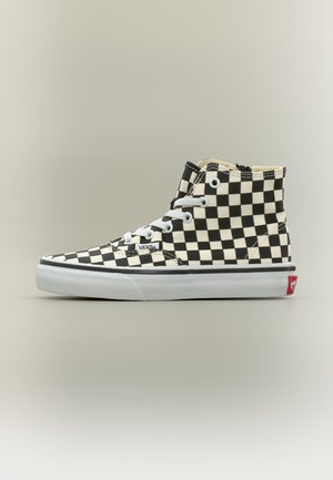 Κλασικό sneaker Vans με ασπρόμαυρο καρό μοτίβο, λευκά κορδόνια και παχιά λευκή ελαστική σόλα με κόκκινη ετικέτα λογότυπου στη φτέρνα.