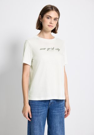 T-shirt à manches courtes de couleur crème claire en coton doux, avec le texte imprimé en vert "new york city" au centre. Design classique à col rond.